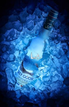 a bottle that is sitting on some rocks with ice and water around it, in the dark