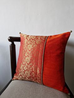 two red and gold pillows sitting on top of a chair