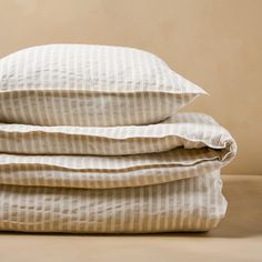 three pillows stacked on top of each other in front of a beige wall and floor