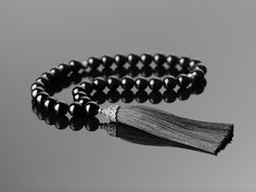 A Touch of Elegance: 33-Bead Black Onyx Tasbih with Tassel for Focused Prayer This 33-bead tasbih transcends the ordinary. Handcrafted from genuine 10mm black onyx beads, it serves as both a sophisticated and serene tool for your dhikr (prayer). Feel the coolness of each onyx bead as it glides smoothly through your fingers, grounding your spirit and promoting focus. The natural weight of the onyx encourages a centered, meditative state, allowing you to connect deeply with your inner peace and spiritual essence. Delicate silver spacers, crafted from 925 sterling silver, elegantly separate the onyx beads, guiding your prayerful journey. More than just prayer beads, this tasbih is a statement piece. The luxurious black hue of the onyx is further enhanced by a striking 8cm tassel, making it a Elegant Gemstone Beads Mala As Gift, Handmade Black Mala As Gift, Elegant Black Rosary With 8mm Beads, Elegant Rosary With Polished Beads For Gift, Elegant Adjustable Rosary With Polished Beads, Elegant Rosary With Polished Beads As Gift, Elegant Gift Rosary With Polished Beads, Elegant Black Rosary As Gift, Traditional Black Rosary As Gift