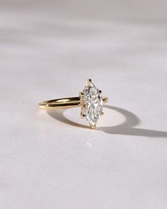 a yellow gold engagement ring with an oval cut diamond in the center, on a white surface