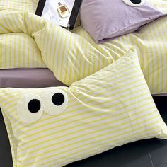 a bed with yellow and white striped sheets, pillows and eyeballs on the covers