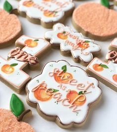 decorated cookies are arranged on a table with green leaves and oranges in the background