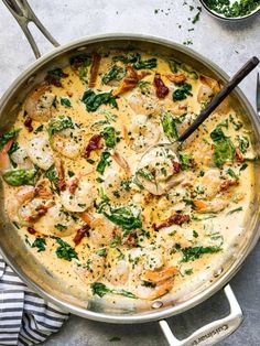 a skillet filled with chicken and spinach covered in cheese on top of a table