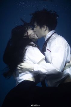 a man and woman kissing under water in an underwater scene with the light shining on them