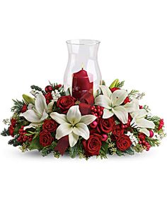 a vase filled with white and red flowers on top of a table next to a candle