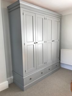 an empty room with white cupboards and carpeted flooring in the corner, next to a radiator