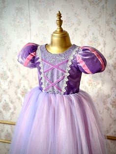 Make your little princess's fairy tale dreams come true with our enchanting Rapunzel costume dress! Perfectly designed for girls, this magical gown features vibrant colors, exquisite lace and ribbon details, and soft, comfortable cotton fabric for all-day play. Ideal for birthdays, dress-up, weddings, photoshoots or any special occasion, let her imagination soar as she steps into the world of enchantment. Let your little one shine and twirl in her very own Rapunzel adventure! ♥ If you want a custom design (in different color, size, fabric, model etc.), please contact us so we can create your dream piece together! * FABRIC: Silk Velvet and long tulle with Cotton lining. * LINING: 100% Organic Soft Cotton (pre-washed and ironed), ensuring utmost comfort for your little one. * DETAILS: The to Rapunzel Dress For Kids, Purple Princess Ball Gown Dress, Pink Fairytale Princess Dress For Pageant, Fairytale Princess Dress For Pageant, Fairytale Tulle Costume Dress, Purple Princess Fitted Ball Gown, Purple Fitted Princess Ball Gown, Fairytale Princess Dress For Pageants, Princess Ball Gown For Pageant