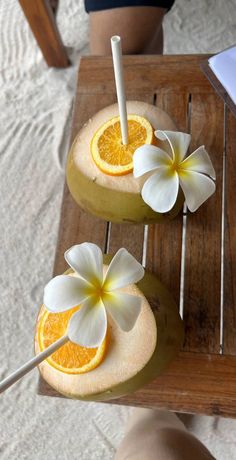 two orange slices with flowers on them sitting on a table next to a woman's legs