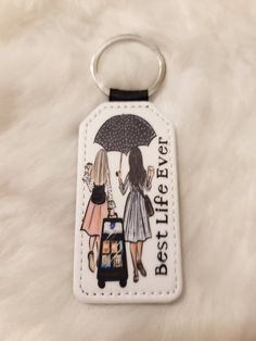 a keychain with an image of two women holding an umbrella and the words best life ever on it