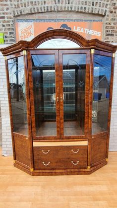 a wooden display case with glass doors in front of a brick wall