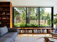 a living room filled with furniture and a book shelf next to a window covered in lots of books