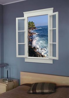 an open window shows the ocean and rocky shore from a bed room with blue walls