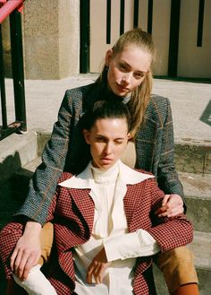 two women are sitting on the steps and one has her arm around the other's shoulder