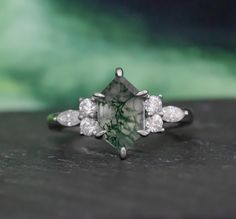 a green and white diamond ring sitting on top of a table