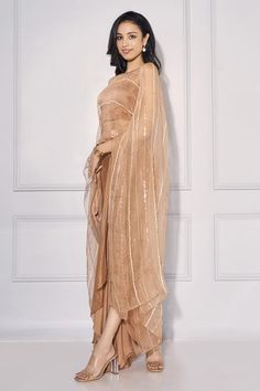 Bronze organza cape with boat neck, stripe pattern, tonal cut work sequin, stone and bead embroidery. Paired with pleated cowl draped dhoti skirt and square neck blouse.
Components: 3
Pattern: Embroidered
Type Of Work: Cut Dana, Stone and Sequin Work
Neckline: Cape: Boat Neck, Blouse: Square Neck
Sleeve Type: Blouse: Sleeveless
Fabric: Crepe, Organza
Color: Brown
Other Details: 
Length:
Blouse: 14 - 15 inches
Skirt: 53 - 54 inches
Attached lining
Note: The belt worn by the model is not for sale Elegant Georgette Cape Dupatta, Elegant Georgette Dupatta In Cape Style, Organza Dupatta With Cape Sleeves For Party, Party Organza Dupatta With Cape Sleeves, Elegant Cape Dupatta For Eid, Floor-length Organza Dupatta For Evening, Elegant Cape-style Dupatta For Reception, Elegant Cape-shaped Dupatta For Reception, Elegant Cape Dupatta For Reception