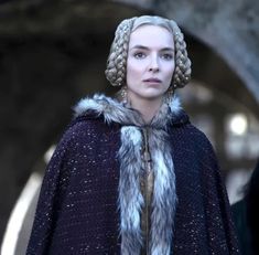 game of thrones character daeneria starke wearing a fur trimmed cape and standing in front of a tunnel