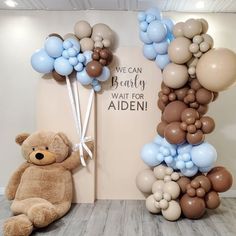 a teddy bear sitting next to a balloon arch