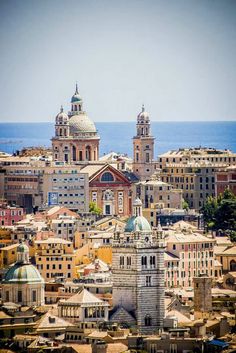 an aerial view of buildings in the city by the ocean with blue sky and water behind them