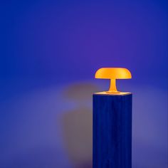 a yellow lamp sitting on top of a blue pillar