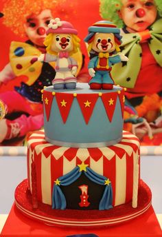 a circus themed cake with clowns on the top and one clown sitting on it