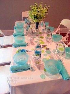 the table is set with blue and green plates, napkins, and vases