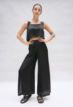 Model is posing in a studio. She is wearing a black crop top and matching wide leg pant in a black silky fabric by Fauna The Label. Versatile Black Viscose Bottoms, Stretch Viscose Ankle-length Wide Leg Pants, Stretch Viscose Wide-leg Pants, Black Full Length Viscose Bottoms, Black Full-length Pants With Side Slits, Black Wide Leg Pants With Side Slits, Viscose Stretch Wide Leg Bottoms, Stretch Viscose Wide Leg Bottoms, Stretch Wide Leg Viscose Bottoms