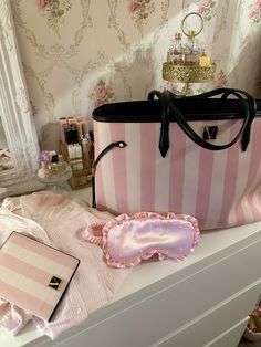 a pink and white striped purse sitting on top of a dresser next to other items