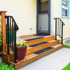 a house with stairs leading up to the front door and flower pots on the steps