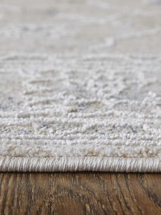 a close up view of a white rug on a wooden floor with a wood table in the background