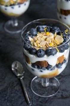 a dessert with blueberries, almonds and yogurt in a glass bowl