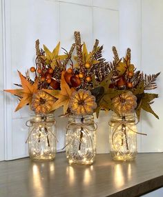 three glass jars filled with flowers and leaves