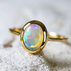 a gold ring with an opalite in the center on top of a rock