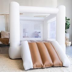 an inflatable bed is on the floor next to a table and chair with a potted plant