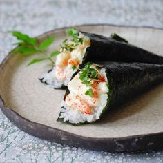 two pieces of sushi on a plate with garnishes and green leaves