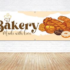 a bakery sign hanging on the wall next to a wooden floor in front of a brick wall