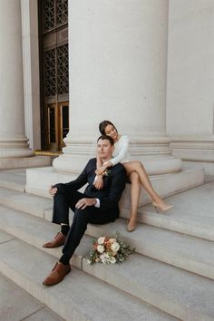 a man and woman sitting on the steps of a building with their arms around each other