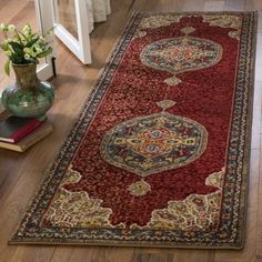 a large red rug on the floor next to a vase with flowers