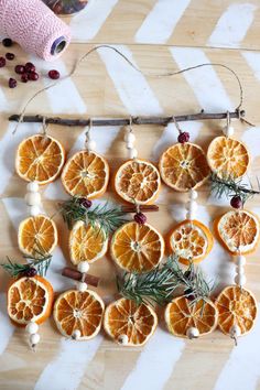 an orange slice garland is hanging on a wooden table with pine needles and dried orange slices