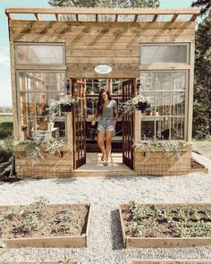 a woman standing in front of a wooden structure with plants growing out of the windows