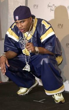 a man kneeling down on the ground in front of a wall with a chain around his neck