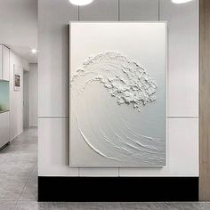 a large white painting hanging on the side of a wall next to a doorway with lights