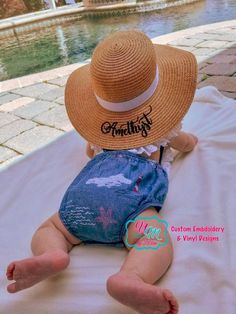 a baby wearing a straw hat sitting on top of a bed next to a pool