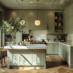 a kitchen with green cabinets and white counter tops, wooden flooring and potted plants on the island