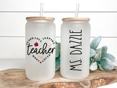 two personalized tumblers sitting next to each other on a piece of wood with succulents