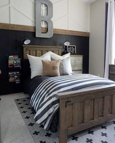 a bed with black and white bedspread sitting next to a wooden headboard