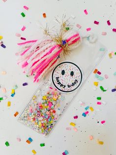 an assortment of sprinkles and confetti on a white surface with a happy face sticker