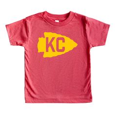 Show your pride as you cheer on Kansas City this season! If you love Kansas City football, tailgating at the stadium, and red and yellow colors, our new KC Arrowhead Football toddler tee is for you! Go Chiefs! One of our most popular tees made in super-soft triblend fabrication is now available for the tots! The triblend fabric creates a vintage, fitted look. Extreme durability makes this t-shirt withstand repeated washings and still remain super comfortable.  FABRICATION * 50% polyester, 25% combed and ring spun cotton, 25% rayon * Side-seamed * Tear away label * Crew neck style * Commercial grade heat press design FIT + COLOR This style is a Bella + Canvas 3413 toddler triblend t-shirt. Most find that the unisex Bella + Canvas shirts are true to size, but may differ from kid to kid. In m Red T-shirt For Football Season, Red Short Sleeve Top For Cheerleading, Cotton T-shirt For Cheerleading In Fan Apparel Style, Cotton T-shirt For Cheerleading Fan Apparel, Red Team Spirit T-shirt For Cheerleading, Red Sports Fan T-shirt For Cheerleading, Game Day Fan Apparel Shirt With Screen Print, Red T-shirt With Team Name For Cheerleading, Screen Print Shirt For Game Day Fan Apparel