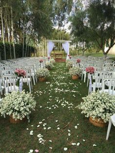 an outdoor ceremony setup with white chairs and flowers on the grass in front of it