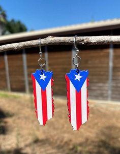 pair of earrings with american flag design hanging from wooden barbwires on outdoor fence